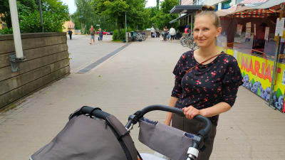 Kvinna med barnvagn ute en sommardag.