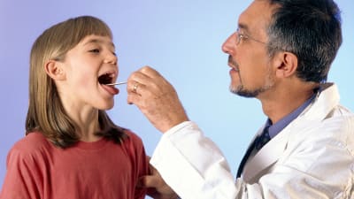 Barnläkare undersöker en flickas hals