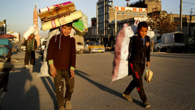Två killar går på gatan i Kabul med stor packning den 26 april 2017