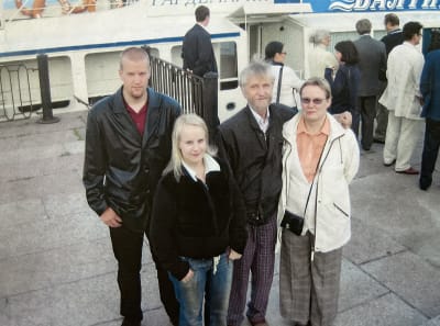Kauko Purasen perhe Pietarissa jokiristeilylaivan edustalla, seisovat vierekkäin ja katsovat kameraan.