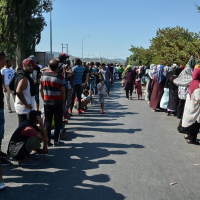 Tusentals flyktingar och migranter har slagit läger vid en landsväg på Lesbos, i stället för att flytta in i ett nytt, tillfälligt läger.