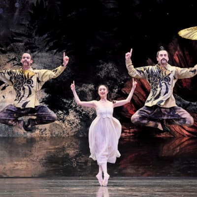 Tre balettdansare som ska föreställa kineser med fingrarna i vädret och solparasoll.
