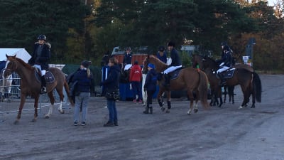 En grupp ryttare på hästar med skötare.