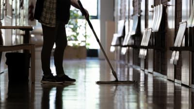 Städare moppar ett golv i en korridor.