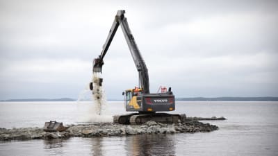 Grävmaskin flyttar en pir.