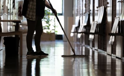 Städare moppar ett golv i en korridor.