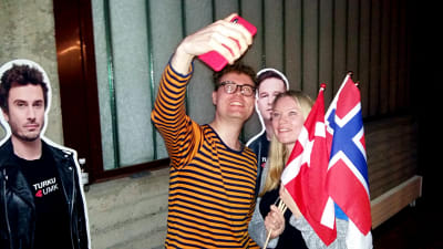 Niklas Ollila och Sonja Bäckman med danska och norska flaggor tar selfie under UMK 2019 med pappfigruen Darude. Pappfiguren Sebastian Rejman får inte var med på deras bild.