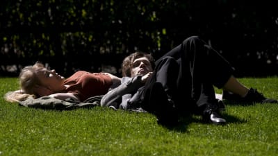 Två personer ligger på rygg i gräset.