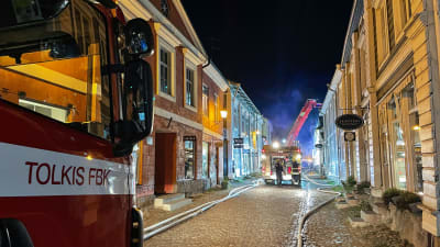Brandbil på Mellangatan i gamla stan i Borgå. Långa slangar längs med marken.