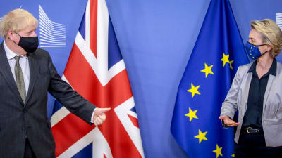 Storbritanniens premiärminister Boris Johnson och EU-kommissionens ordförande Ursula von der Leyen tittar mot varandra. Johnson står framför Storbritanniens flagga, von der Leyen framför EU:s flagga. Johnson visar tummen upp. Bilden tagen 9.12.2020.