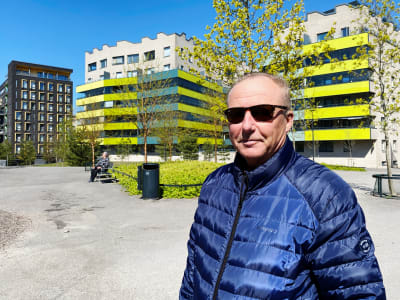 Kari Mäenpää framför en park och bostadshus.