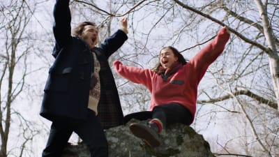 Gösta (Vilhelm Blomgren) och flickvännen Melissa (Amy Deasismont) står på en sten och hurrar. 