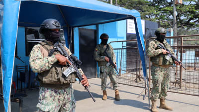 Tre poliser beväpnade med stormgevär vaktar ingången till fängelset Penitenciaría del Litoral i Guyaquil i Ecuador.
