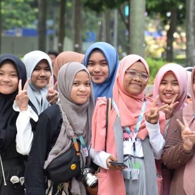 En grupp muslimska flickor i Malaysia poserar för kameran och gör segertecken med fingrarna.