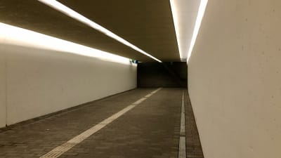 En tunnel med vita väggar och asfalterat golv. 