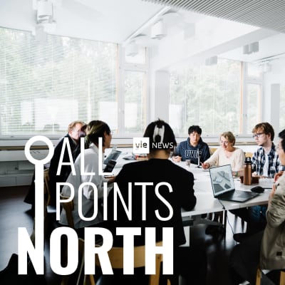 Kuvassa istuu valkoisen pöydän ääressä joukko Aalto-yliopiston arkkitehtuuriopiskelijoita. Osalla opiskelijoista on kannettavat tietokoneet edessään pöydällä.