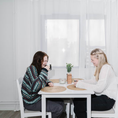Maria Kavonius ja Iida Ulkuniemi istuvat pöydän ääressä juomassa kahvia.