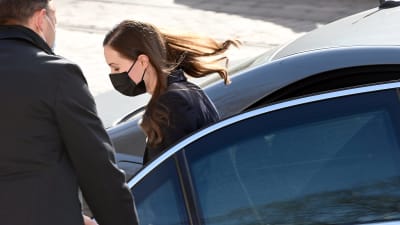 Statsminister Sanna Marin stiger ur baksätet på en bil. En man håller upp dörren åt henne.