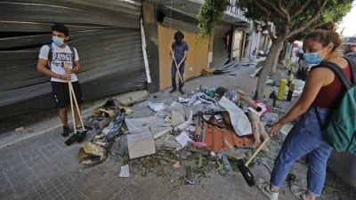 Personer städar gatan efter explosionen i Beirut.