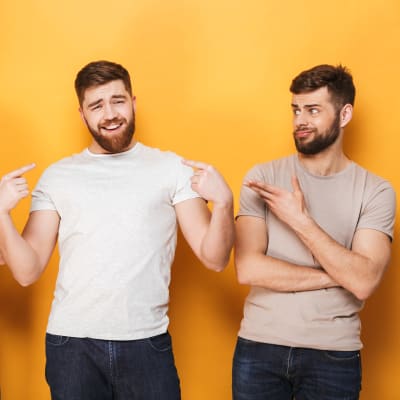 Tre unga män i ljus t-skjortor, den i mitten ler självsäkert medan de andra tittar surt på honom