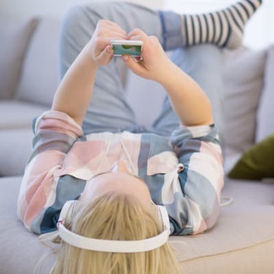 En flicka ligger i soffan och lyssnar på musik