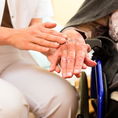 Vårdare håller äldres hand. 