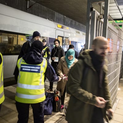 Gränskontrollanter i reflexväst kollar ID på tågpassagerare i Malmö.