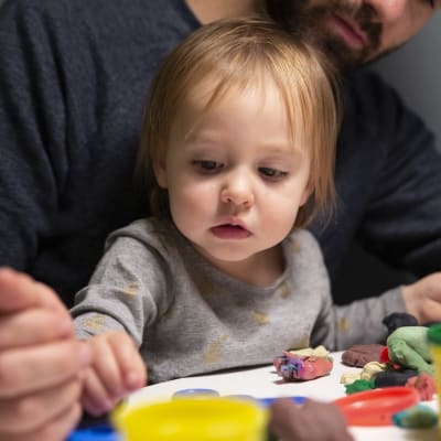 Ett och ett halvt-åriga Mathilda leker i pappas famn.