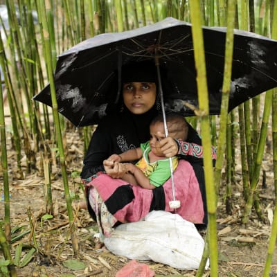 En rohingyaflykting har tagit skydd under ett paraply med sin baby i flyktinglägret Thangkhali, Coxbazar, Bangladesh 12.10.2017.