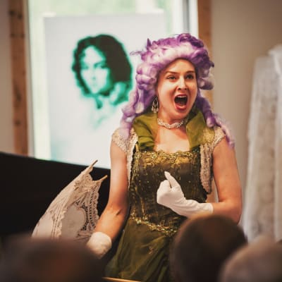En sångerska klädd i peruk sjunger opera.