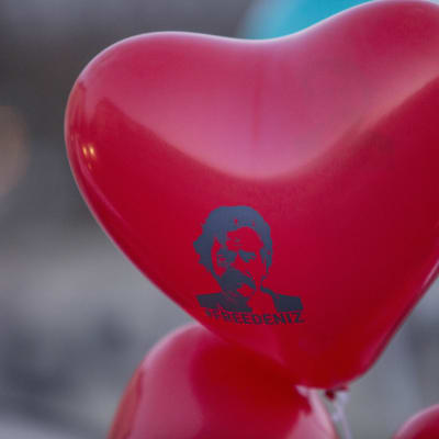 En röd hjärtformad ballong med bild på Denis Yücel och texten #freedeniz