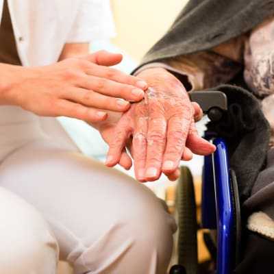 Vårdare håller äldres hand. 
