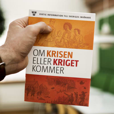 En hand håller upp en broschyr med texten "om krisen eller kriget kommer".