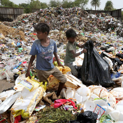 Indiska barn omgivna av avfallshögar