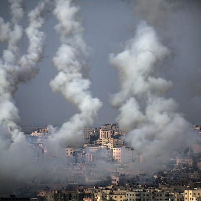 Gazasta lähteneet rakettien savuvanat taivaalla kaupungin yläpuolella.