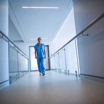 En sjukskötare fotograferad nerifrån medan hon går i en sjukhuskorridor.