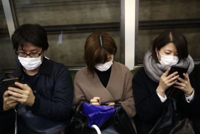 Passagerare på metron i Tokyo. De har alla ansiktsmasker.