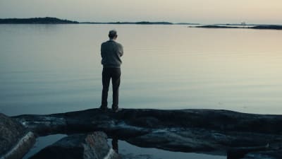 Anders Larsson tittar mot horisonten vid havsstranden. 