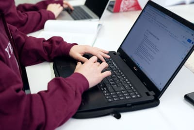 En elev pluggar. Hen skriver på datorn.