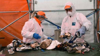 Bild av männsikor i skyddsytrustning som sorterar sopor. 
