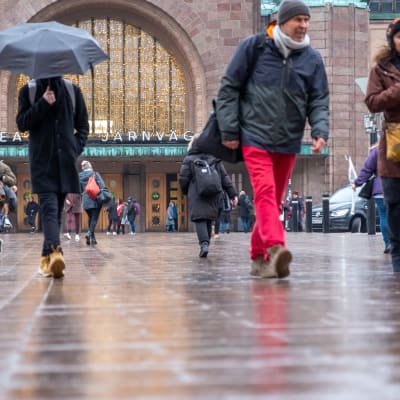 Ihmisiä kävelemässä Helsingin päärautatieaseman sisäänkäynnin edustalla.