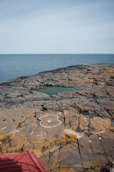 Utsikt över havet, i förgrunden en klippa med en helikopterlandningsruta utmärkt med en vit cirkel och bokstaven H.
