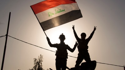 Irakiska regeringsstyrkor viftar med nationsflaggan i Mosul.