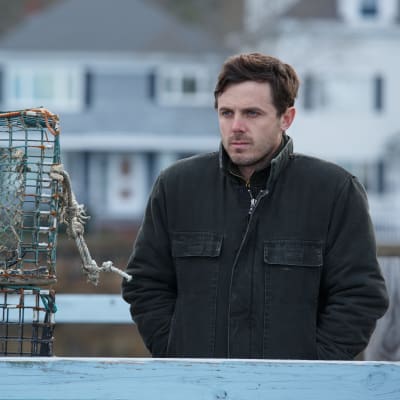 Lee (Casey Affleck) står på en brygga och ser sorgsen ut.