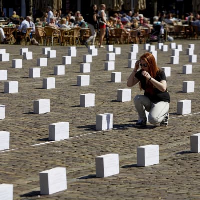 Medlem i Amnesty International placerar ut symboliska gravstenar i Amsterdam till minne av de hundratals migranter som har drunknat i Medelhavet under färden till Europa.