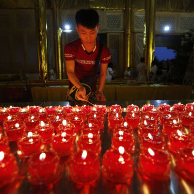 En person tänder ett ljus i ett tempel i Tianjin till  minnet av de döda i explosionerna.