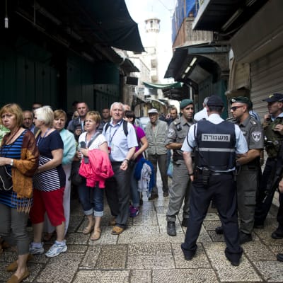Turister passerar israeliska poliser efter en knivattack i Jerusalem den 7 oktober 2015.
