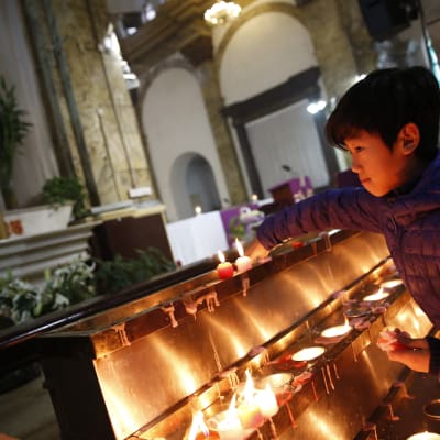 En pojke tänder ett ljus i en katolsk kyrka i Peking.