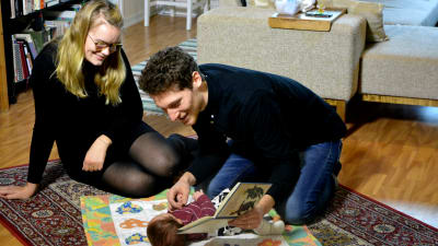 Petronella Nordman och Markus Bergfors sitter på golvet och läser för sin två månader gamla son Roy som ligger på en filt.