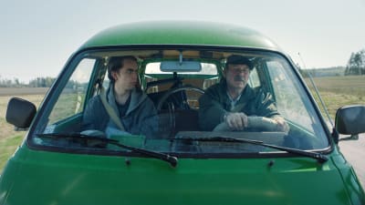 Stefan (Martin Paul) och Nisse (Peik Stenberg) sitter tillsammans i en grön paketbil. 